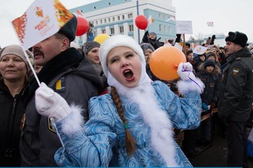 Menina comemora passagem da tocha olímpica ao lado de policiais russos / Foto: Divulgação Sochi 2014